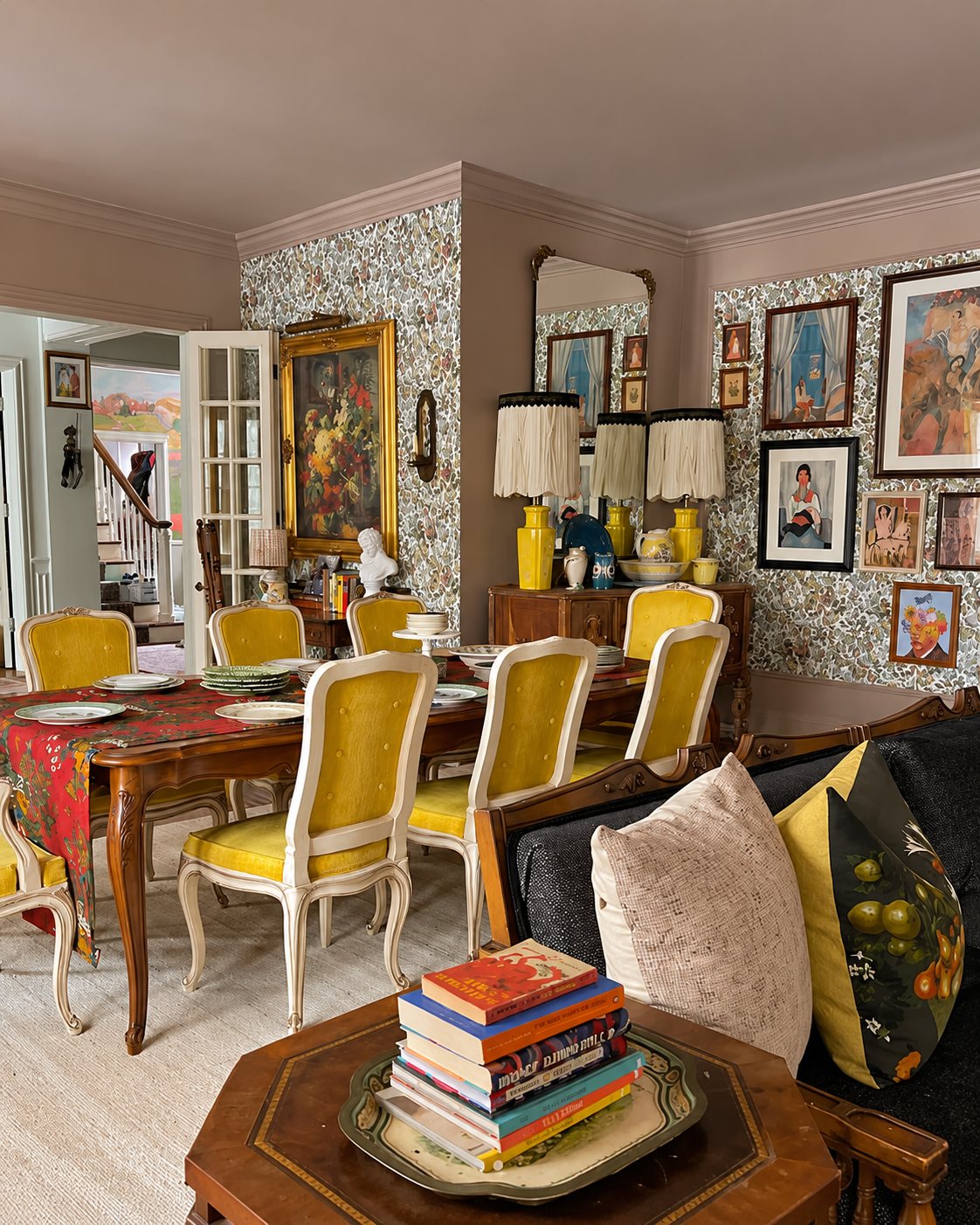 Dining room with floral wallpaper, yellow chairs and a salon-style gallery wall